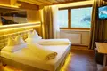 Hotelzimmer mit Holzdecke und -wand, indirekter Beleuchtung und Fernseher