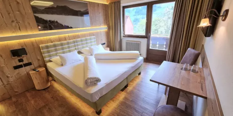 Hotelzimmer mit Holzdecke, Fernseher, Schreibtisch und Balkon