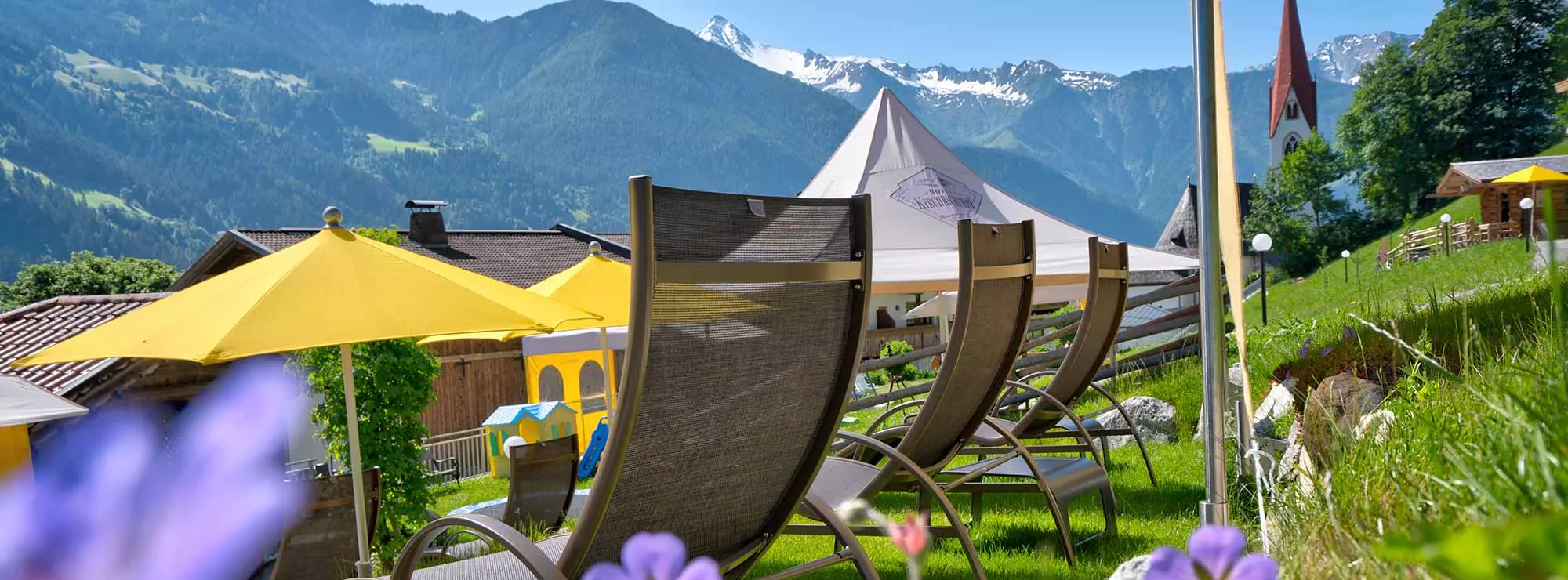 Liegestühle mit Sonnenschirmen in der Sonne im Garten im Hippach in den Bergen