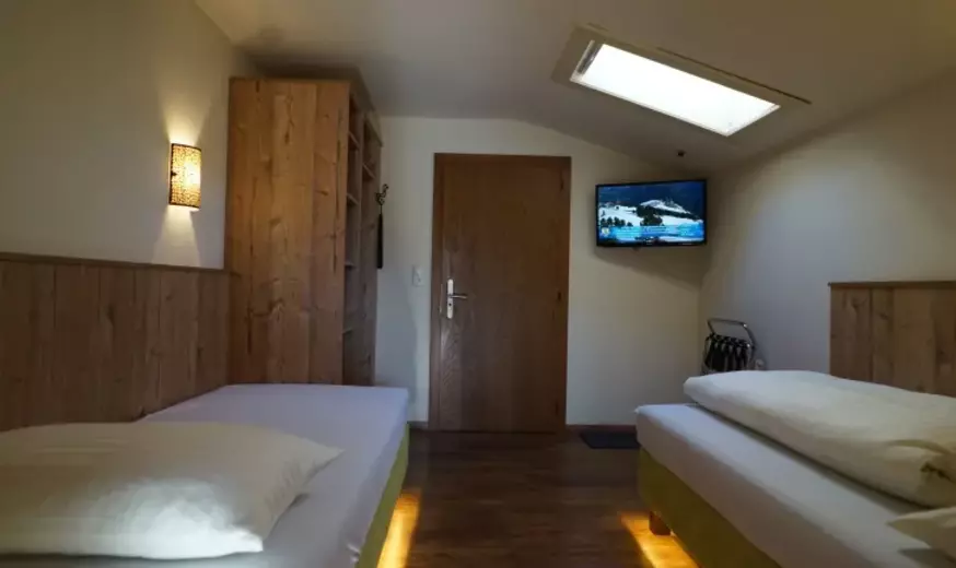 Hotelzimmer mit Einzelbetten und Dachschräge mit Dachfenster