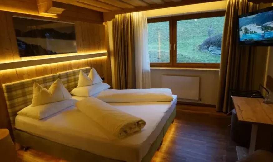 Hotelzimmer mit Holzdecke und -wand, indirekter Beleuchtung und Fernseher