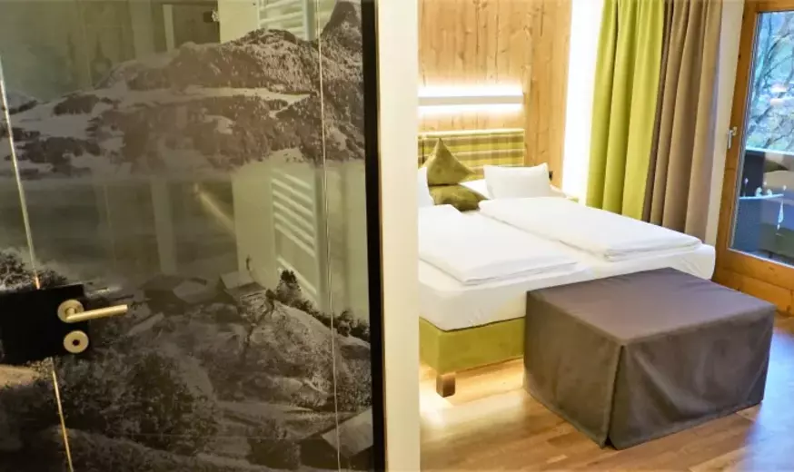 Schlafzimmer mit indirekter Beleuchtung an den Betten und Balkon