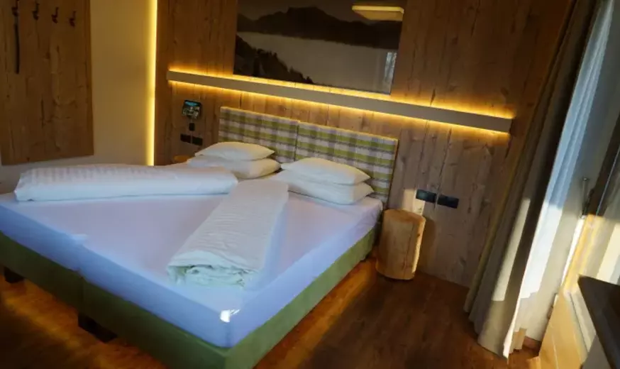 Schlafzimmer mit indirekter Nachttischbeleuchtung und holzvertäfelter Wand
