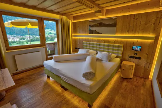 Hotelzimmer mit Wänden und Decke aus Holz, Fernseher und Balkon