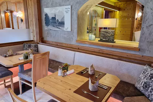 Speisesaal mit Holzvertäfelung, gepolsterten Stühlen und gemütlicher Sitzgarnitur