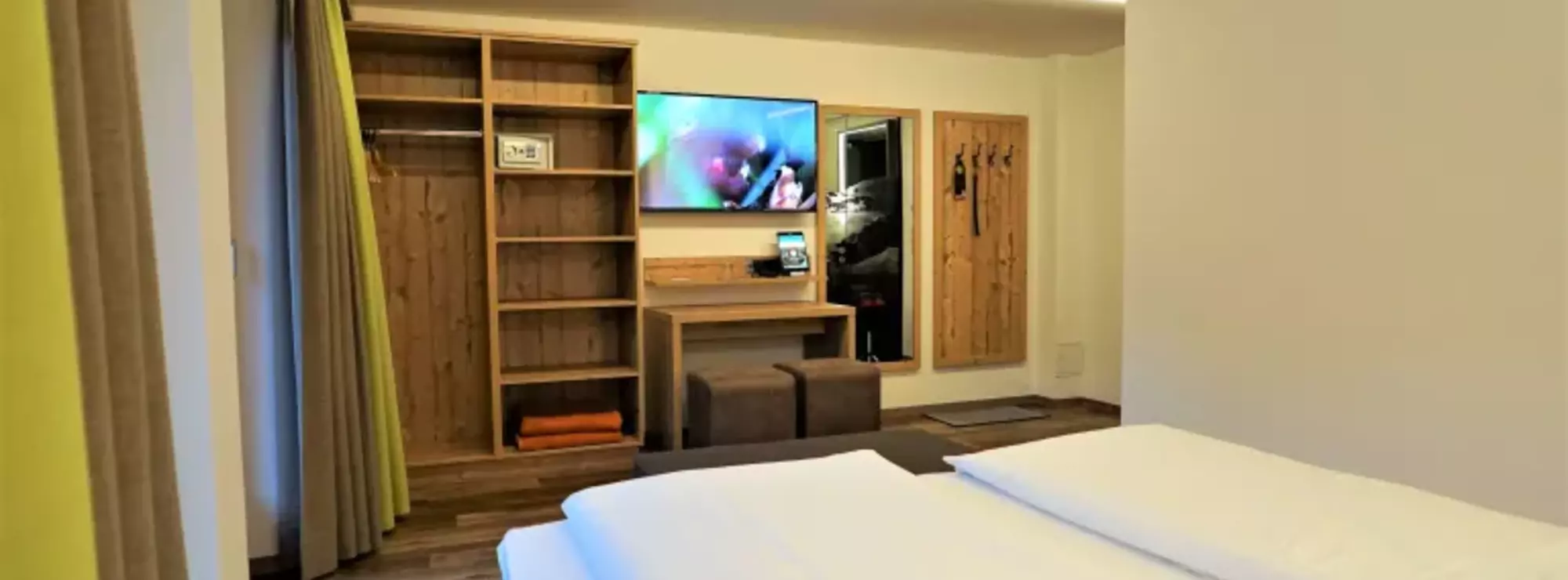 Schlafzimmer mit Kleiderschrank, Garderobe, Wandspiegel und Fernseher